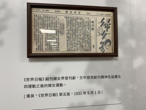 preserved portion of a newspaper, framed and displayed on a wall with a descriptive caption (in Chinese)